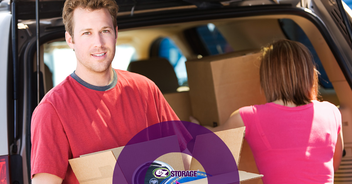 Woman and smiling man loading boxes into SUV