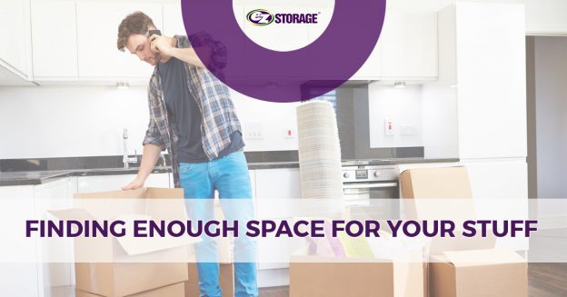 Man on phone in an empty kitchen with open moving boxes on the ground around him