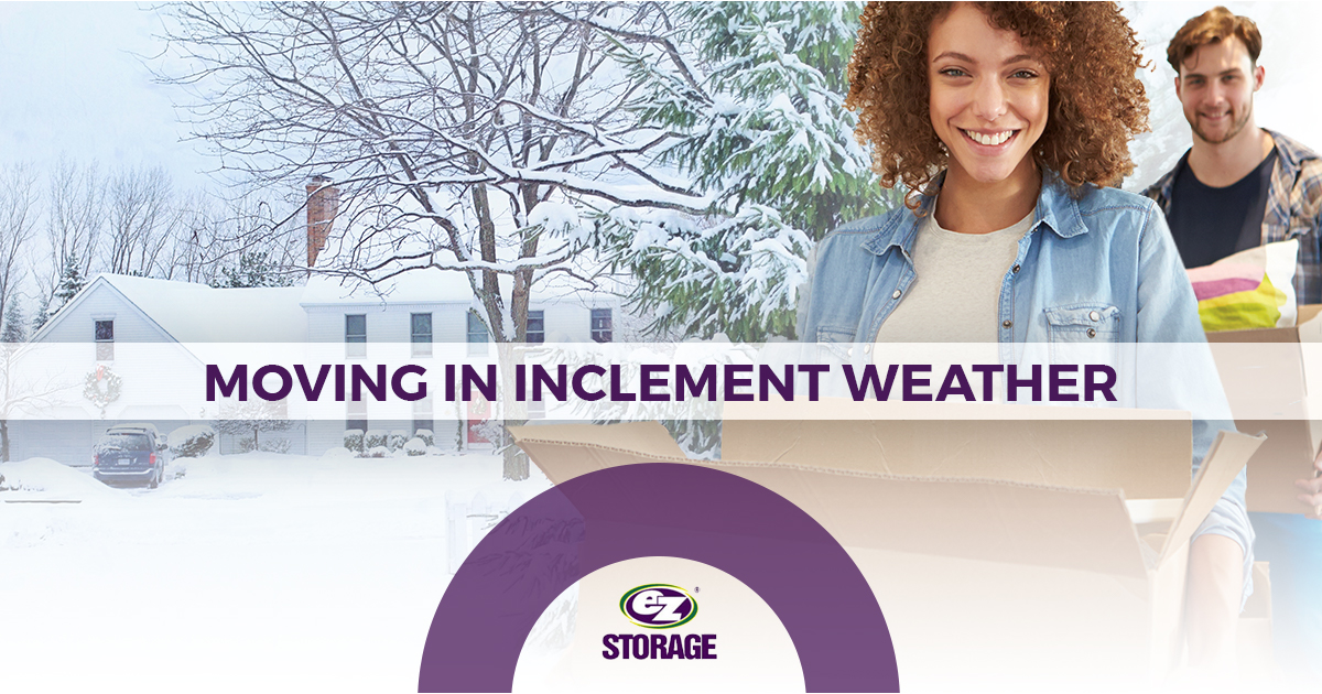 Man and woman carrying moving boxes outside snow-covered home with EZ Storage logo and text "Moving in Inclement Weather"