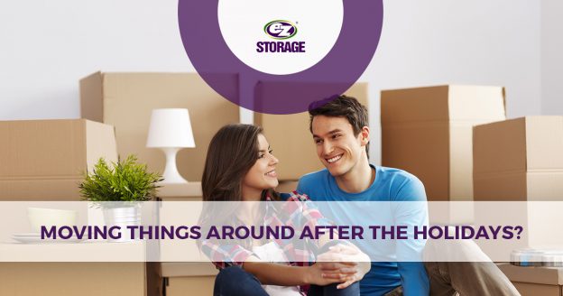 Man and woman smiling at each other in front of moving boxes with EZ Storage logo and text "Moving Things Around After the Holidays?"