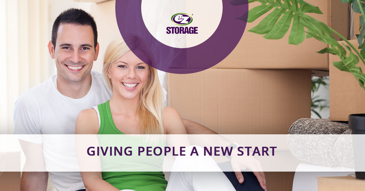 Couple sitting down on the floor smiling and text "Giving people a new start"