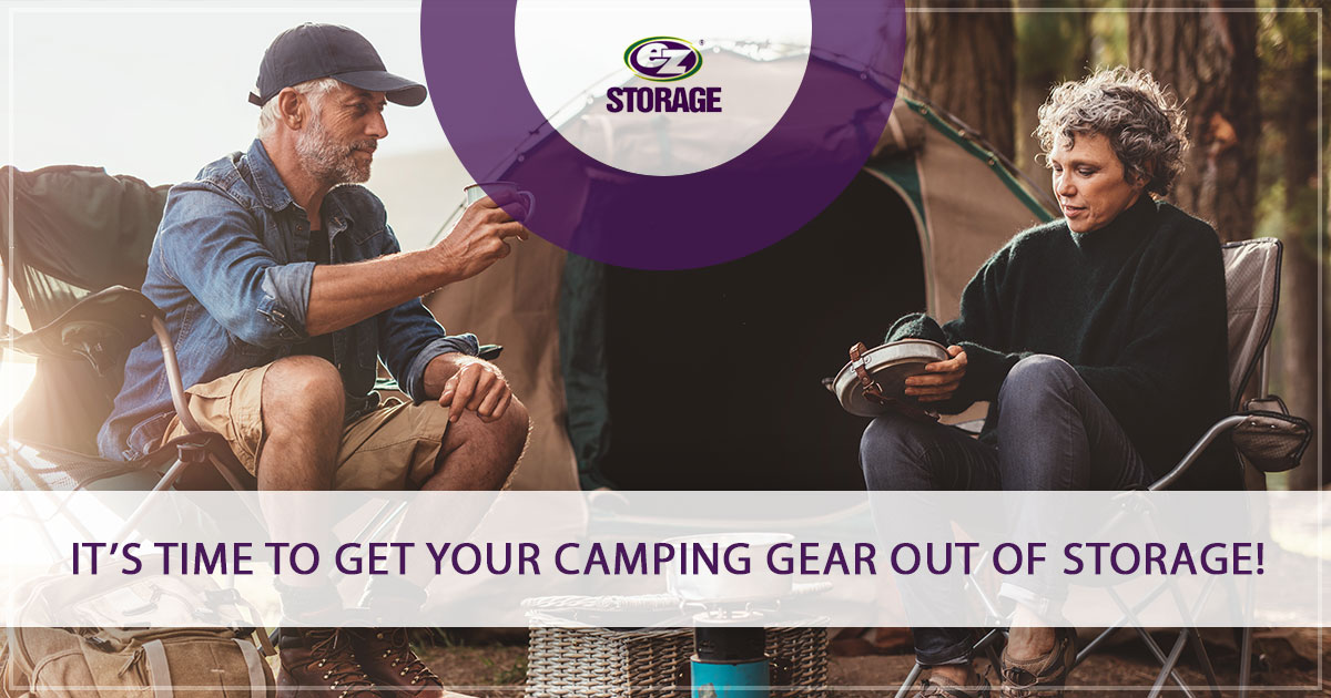 Older man and woman sitting in camp chairs outside of tent drinking coffee with EZ Storage logo and text "It's Time To Get Your Camping Gear Out Of Storage!"