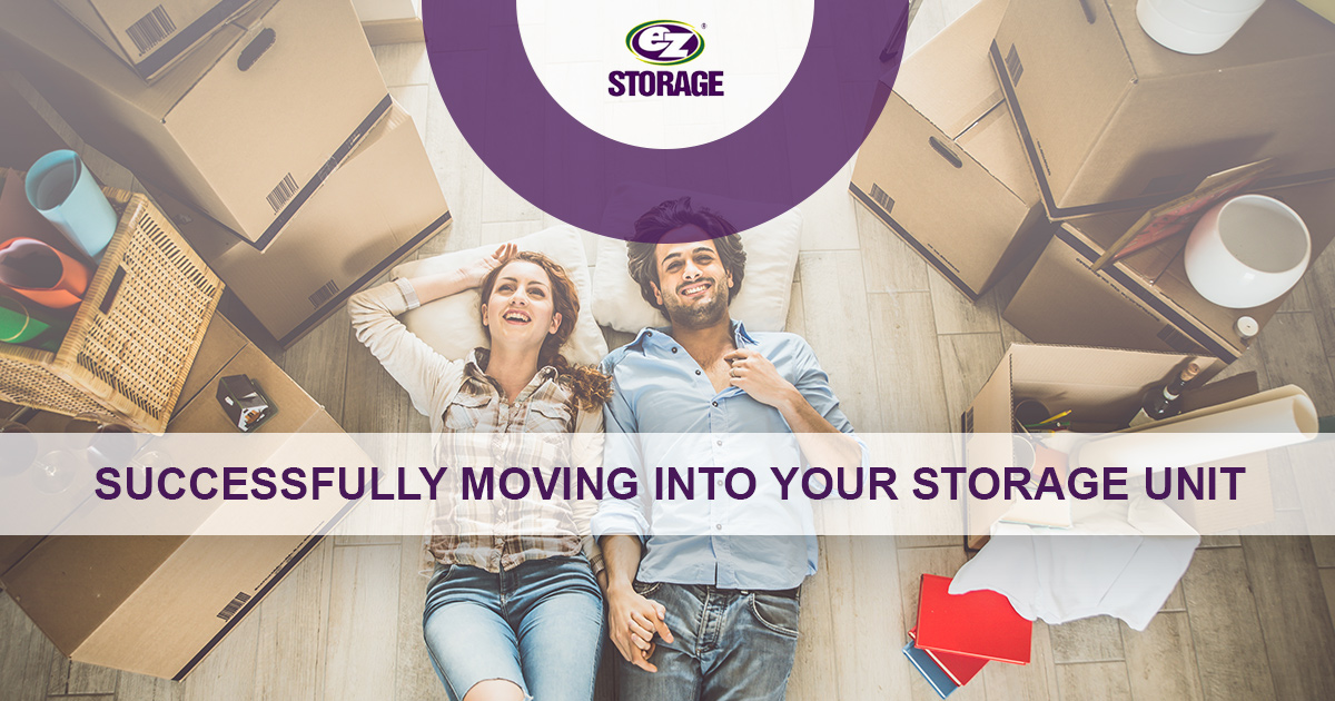 Couple laying down on the floor surrounded by boxes and text "Successfully moving into your storage unit"