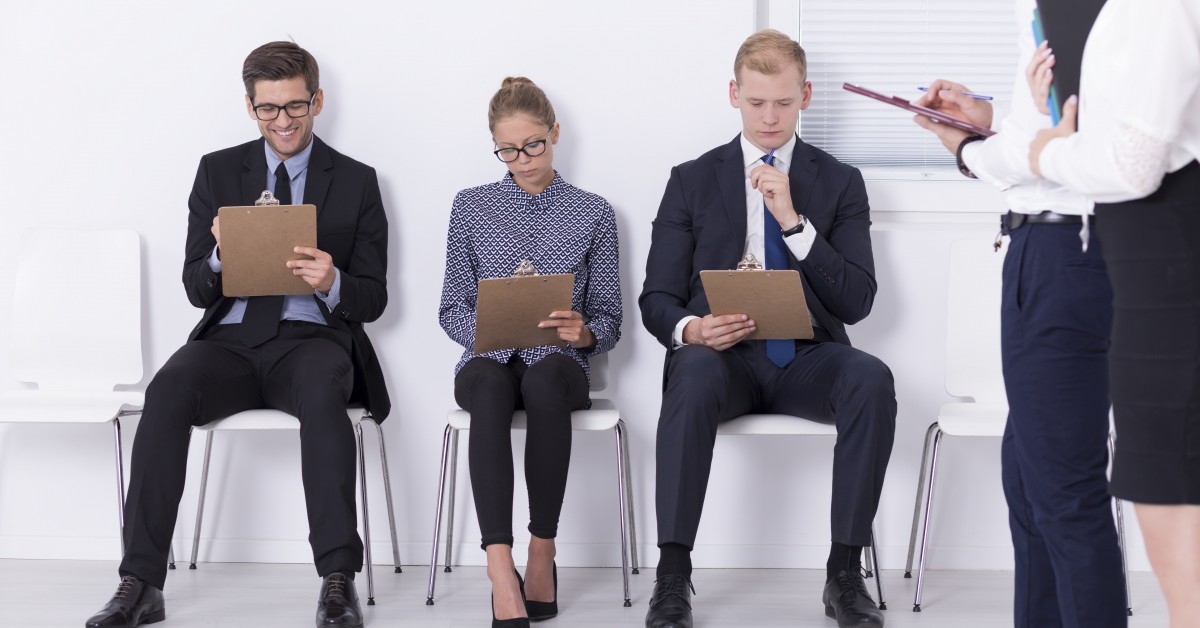 Two men and one woman in business clothes filling out paperwork