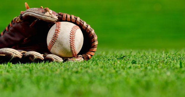 Close-up of baseball mitt laying on the ground with a baseball