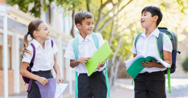 Three young students in uniform with folders in hands