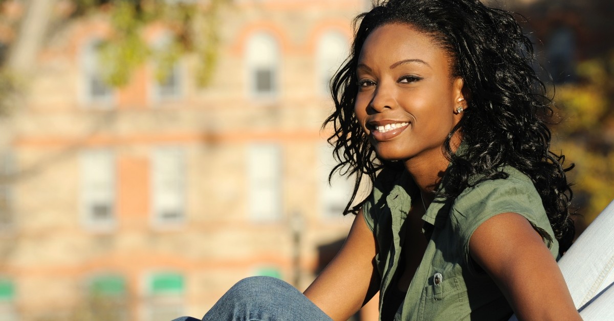 Female, college-aged student sitting outside in a campus setting