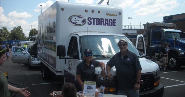 Frontal view of an EZ Storage moving truck with people facing camera & smiling