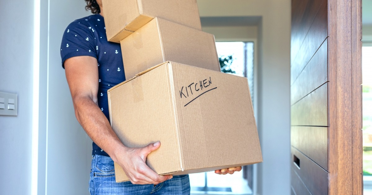 Close up of man holding boxes for moving labeled with text "kitchen"