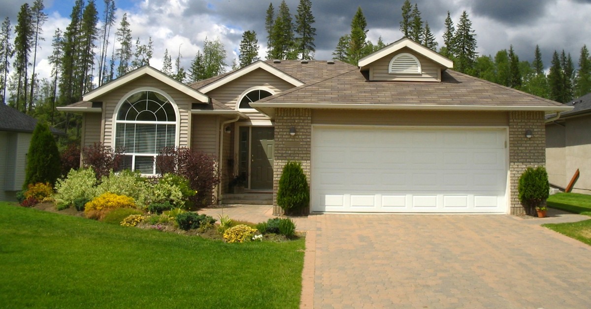 Frontal view of a one-story residential home with manicured green lawn and driveway.