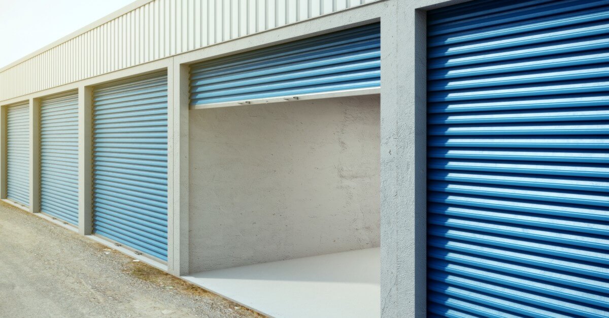 Exterior view of storage unit facility with blue shuttered doors and one door open