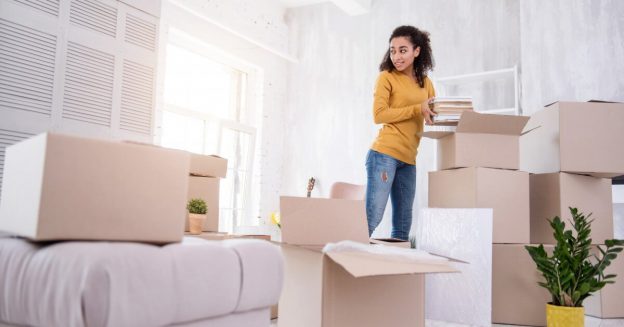 Woman standing in room full of moving boxes.