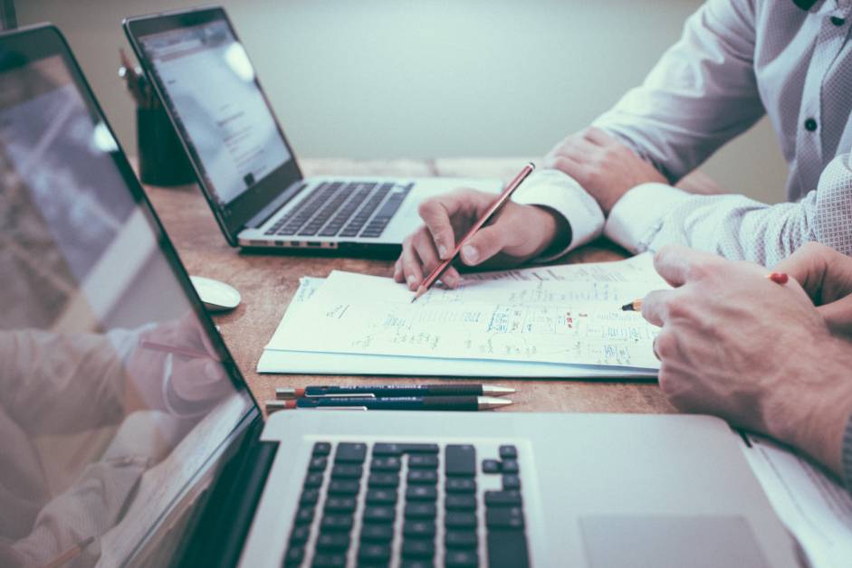 Two men working on business documents and laptops