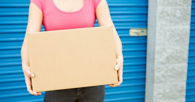 Closeup of woman holding a moving box outside a storage space