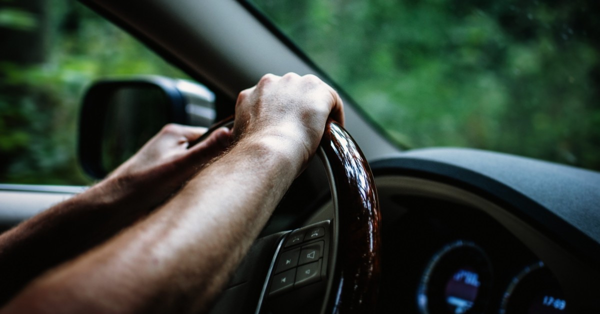 Closeup view of hands holding a steering wheel while driving