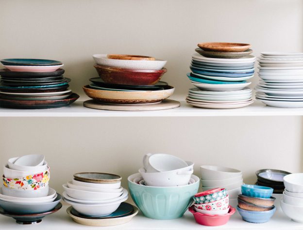 Multicolored dishes, bowls, and cups on white shelf