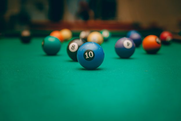 brightly colored pool balls on green felt pool table